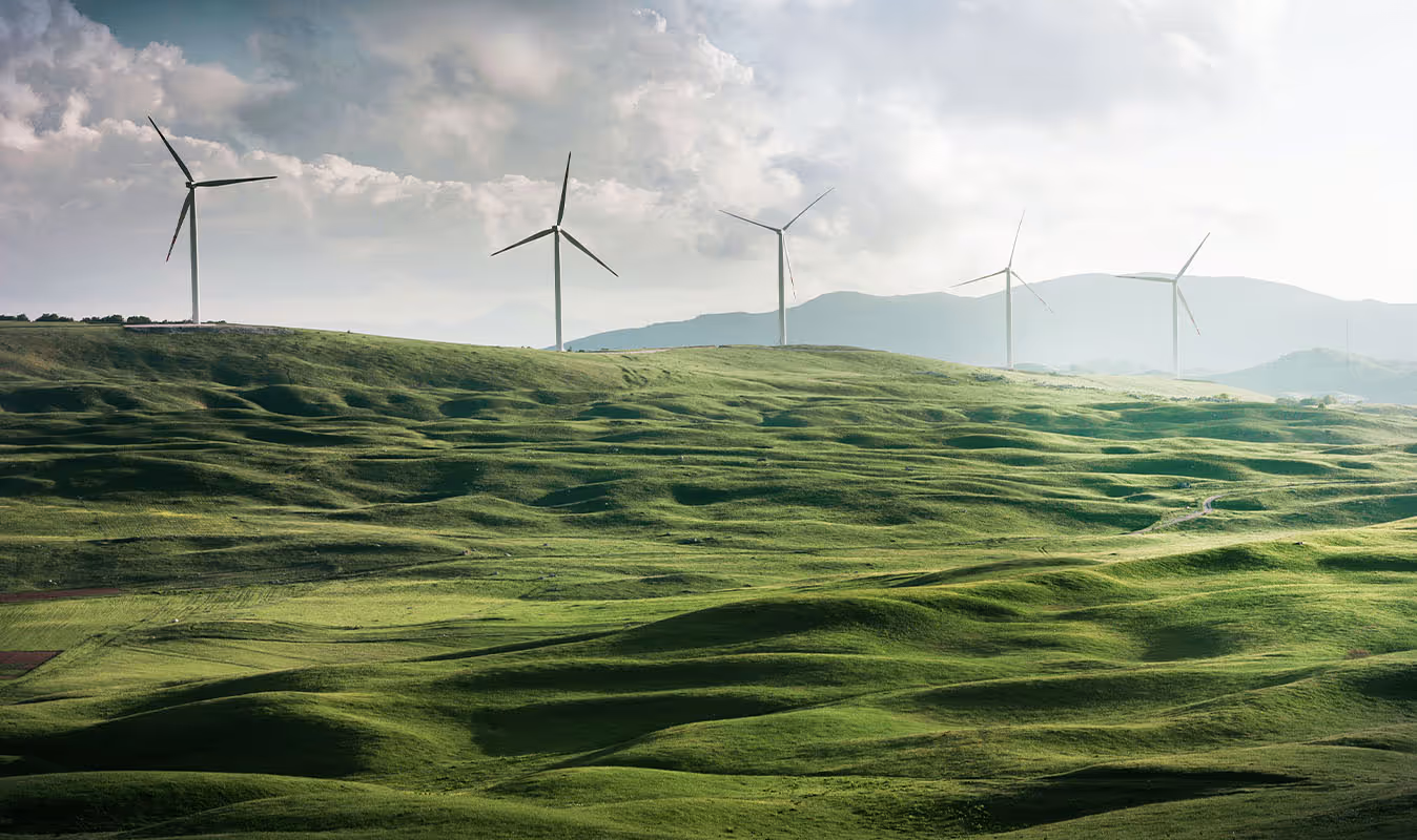A row of wind turbines on a grassy hill